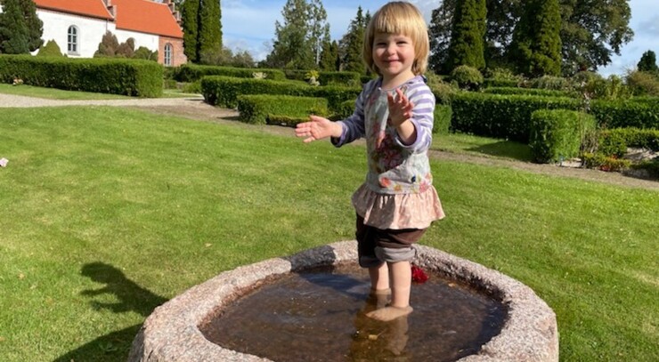 Barn stående i døbefont udenfor