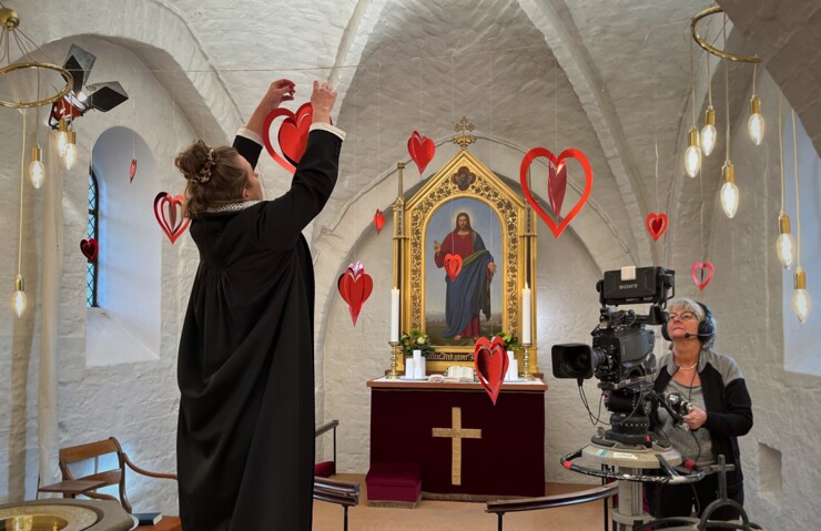 Præst Ane Øland Bækgaard pynter op i kirken, inden optagelserne går i gang.